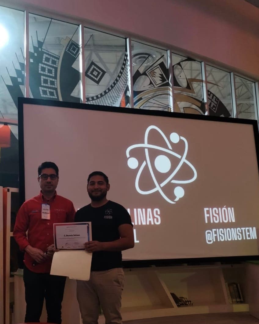 Ramses recibiendo un reconocimiento de Fisión frente al logo @fisionstem.